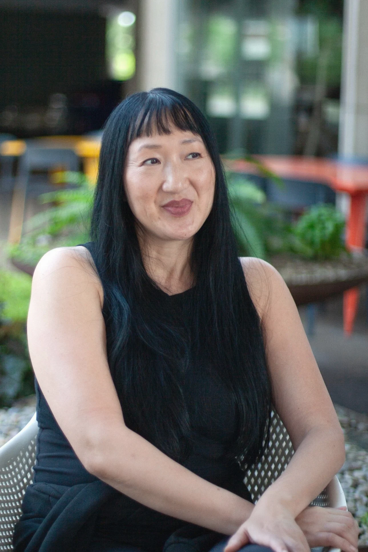 Karin "Kay" Whang seated outdoors, smiling for a portrait