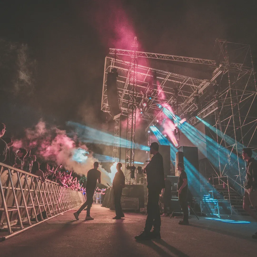 A live concert stage lit in pink and blue as the audience gathers